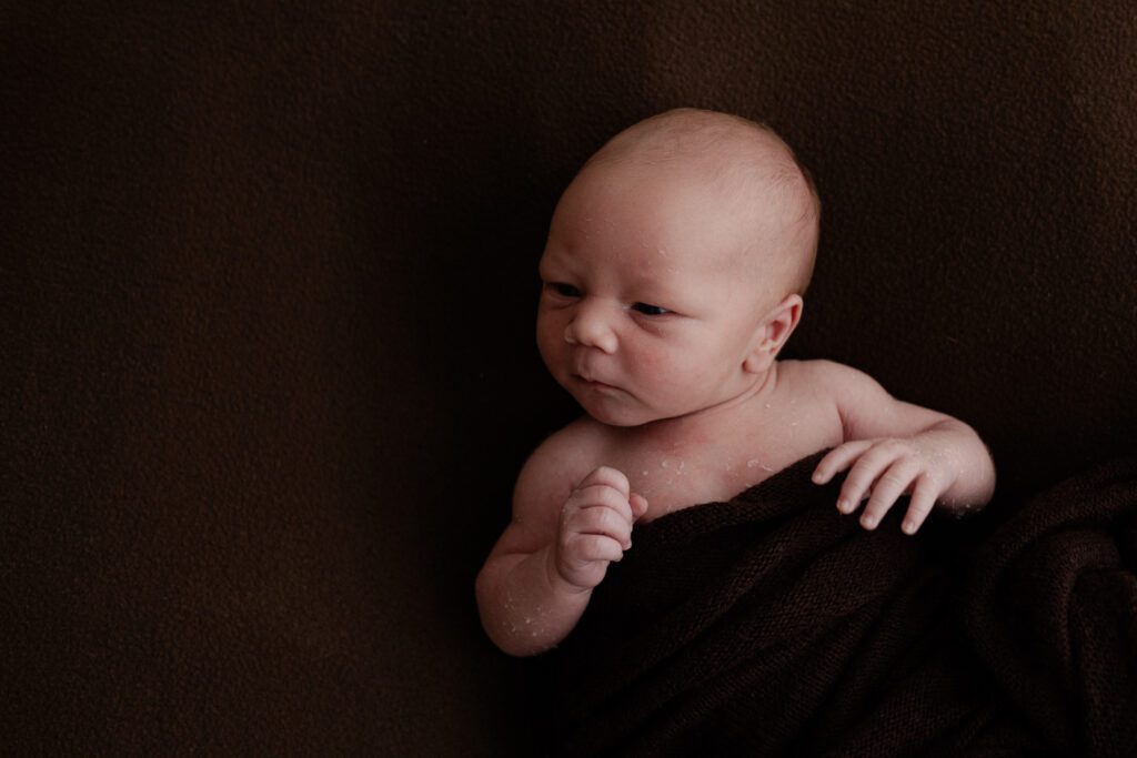Wakkere baby tijdens de newbornshoot thuis. Irene Maris Fotografie Brabant.
