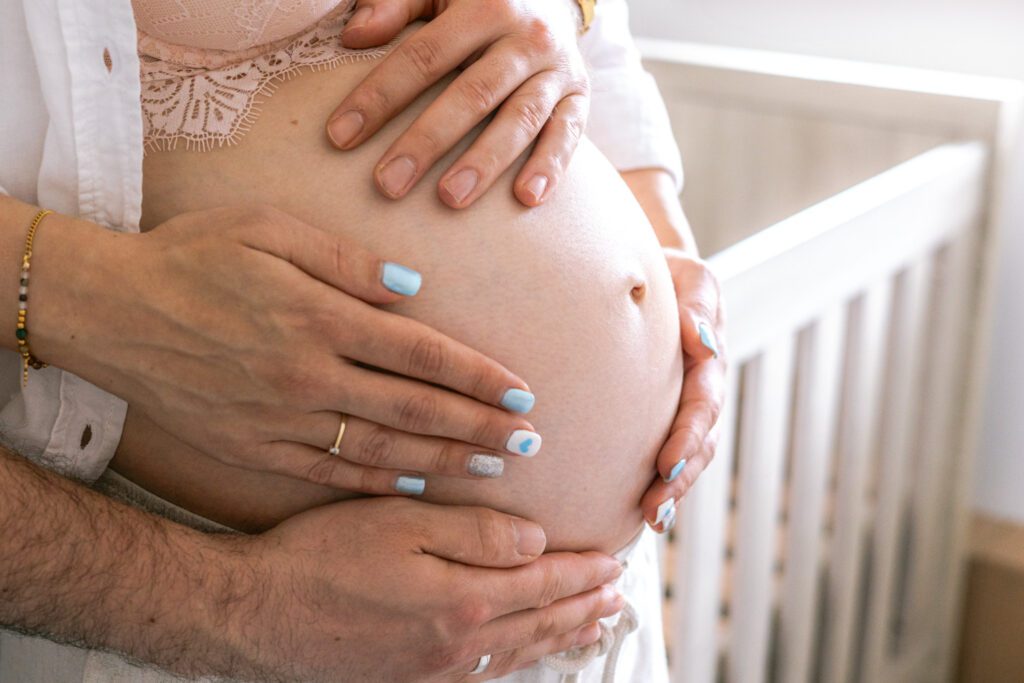 Zwangerschapsshoot bij je thuis. Close up foto van zwangere buik met handen van papa en mama. Irene Maris Fotografie